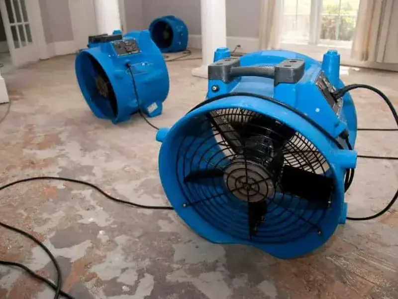Several air movers set across a wet floor to start the drying