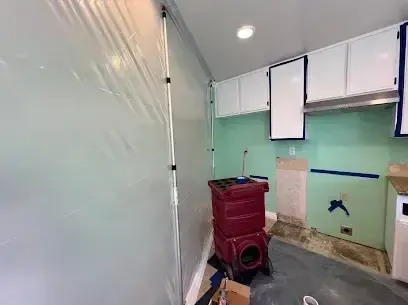Containment plastic and a dehumidifier set up inside a kitchen work area