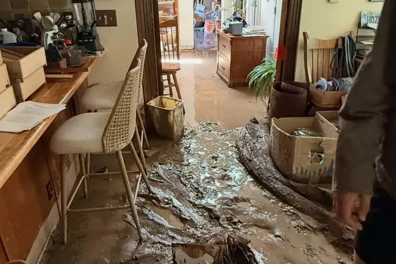 Mud and floodwater spread across a kitchen floor after a flood