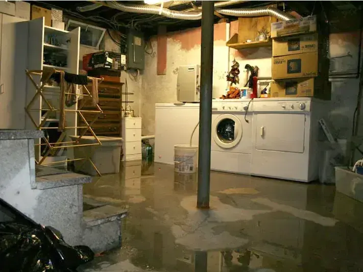 Standing water spread across a flooded basement laundry room