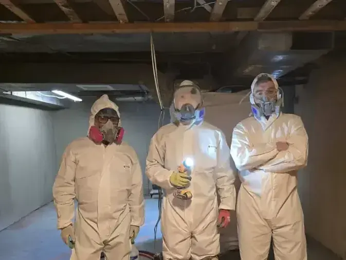 Workers in protective suits and respirators during a basement sewage cleanup